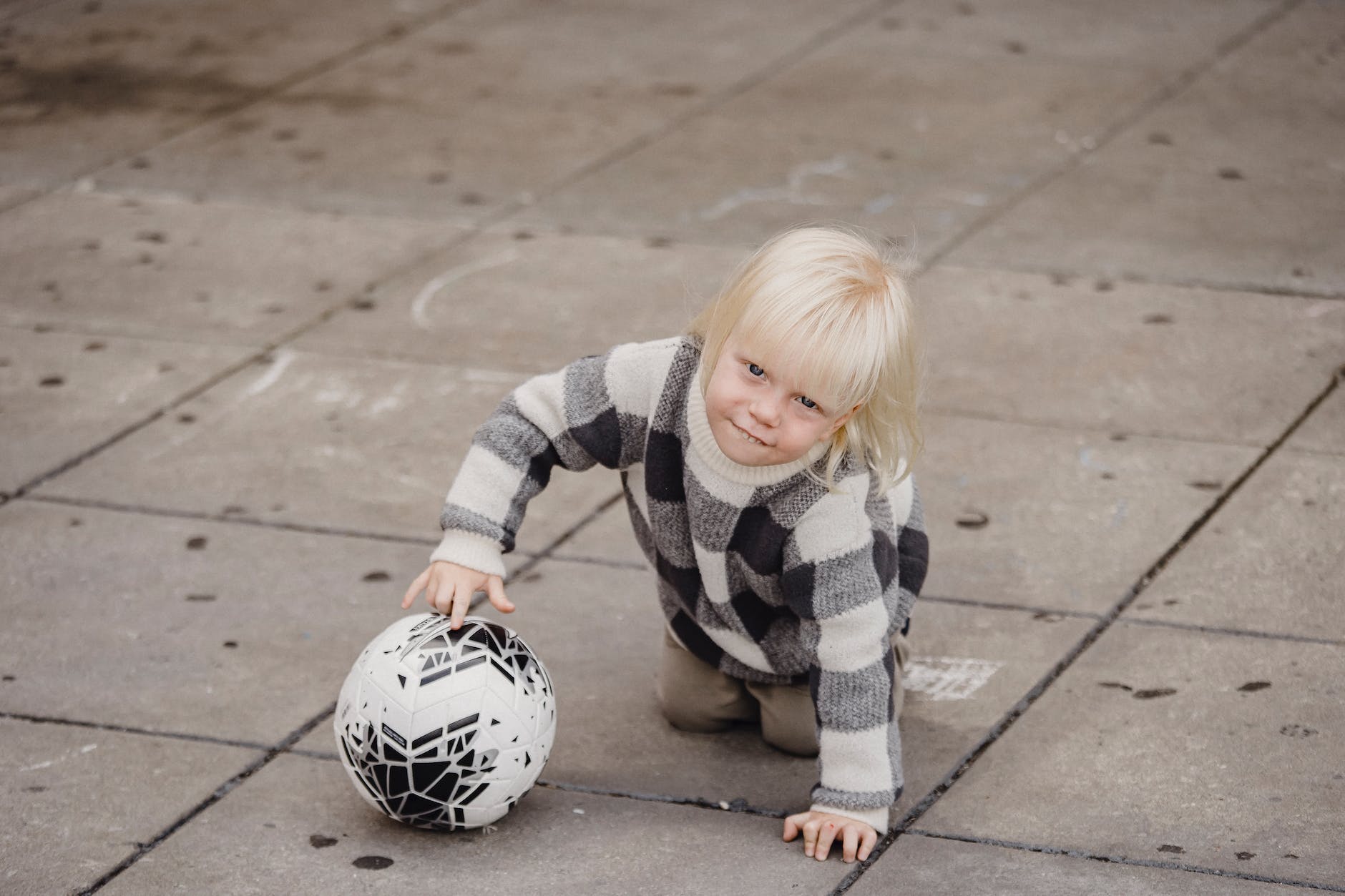 little kid rolling ball on playground