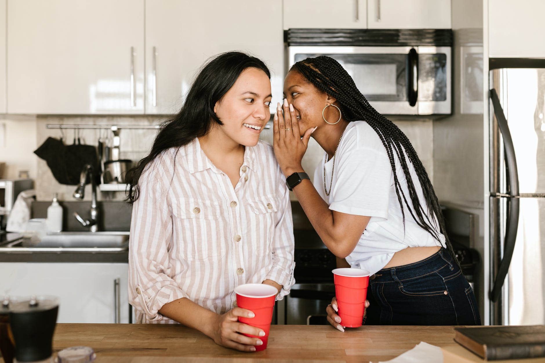 a young woman whispering to her friend at a party